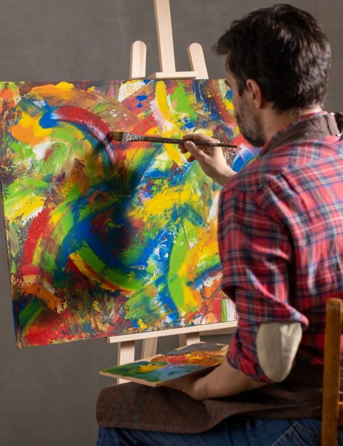Male artist working on painting. Man artist painter in creative studio